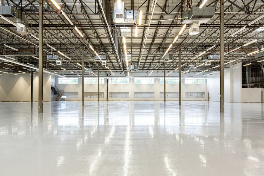 The interior of a modern distribution warehouse, the lighting grid visible across the roof structure.