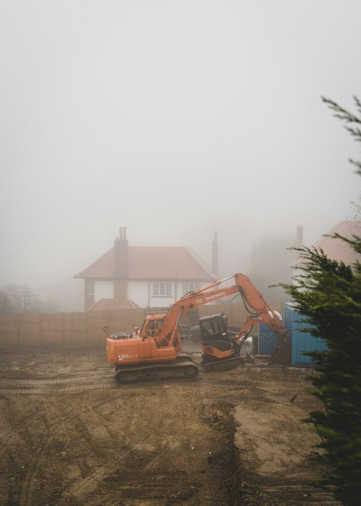 An excavator working on a misty housing development site.