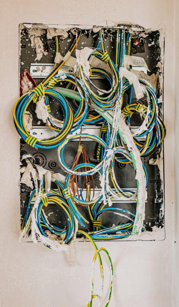 A crowded back box of old wiring in a plastered wall, of the kind found in ageing terraced housing.
