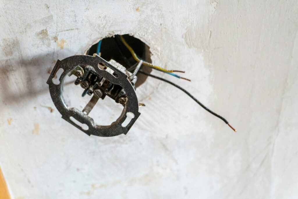 An open ceiling junction box with lighting cables during a renovation.