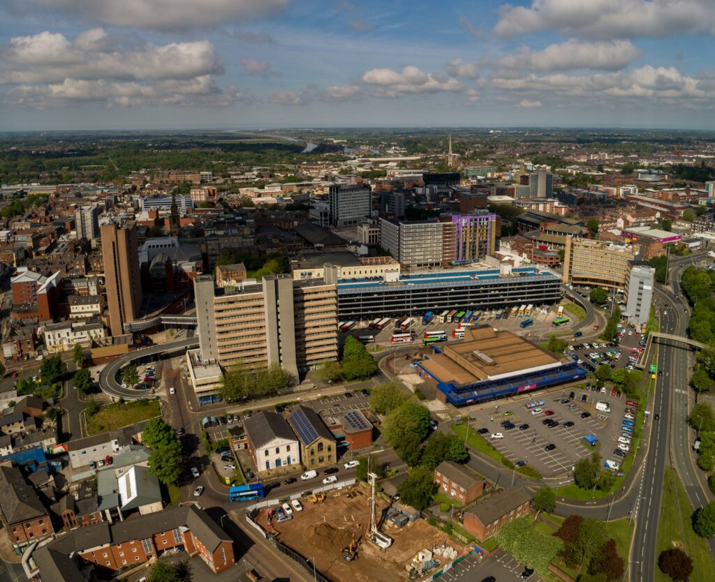 Aerial view over Preston city centre, with the concrete decks of Preston Bus Station in the foreground and St Walburge's spire beyond.